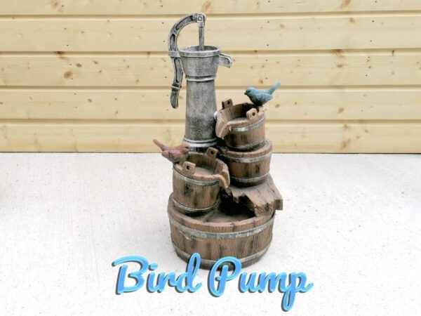 The Bird Pump Water feature against a wooden shed. It is a large enough sized water feature with three buckets and two birds, one red, one blue - on it.