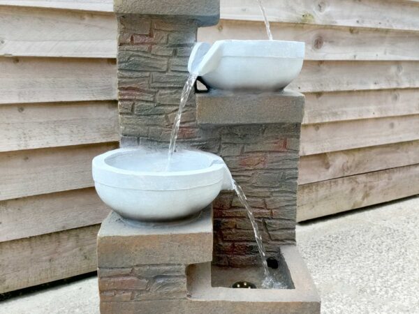 The Cascades Water Feature against a wooden shed