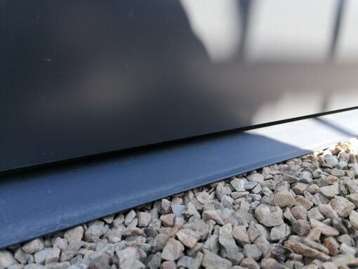 A macro photo of the lipped entry into the premium panoramic garden shed. It is a dark-grey metal strip with a slow incline and the edges are curled to prevent punctures