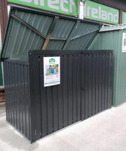 The bin store as seen from a 45 degree angle. The lid is open showing the paler grey colour that is on the inside. The unit itself is a dark grey and there is a white rectangular piece of paper on the front of it while denote the details of the shed to customers