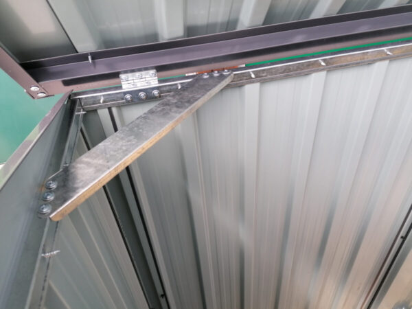 The internal brace bar of the 3-bin store. It's a shiny, silver colour and it creates a right angled triangle with the edges of the unit