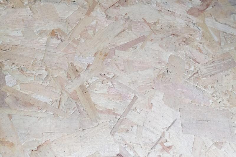 A close up view of OSB board, that shows the various strands of wood that have been pushed together to form the board