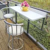 The large white balcony table on a balcony with pink flowers in a yellow plant pot on top