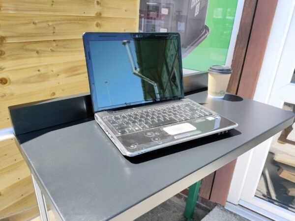 The black balcony table with a laptop and coffee cup on it