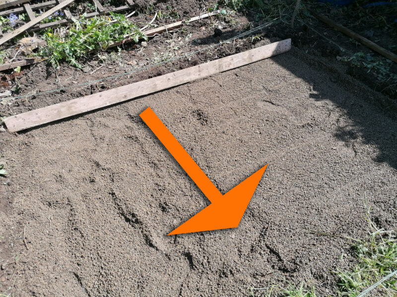 a relatively flat piece of gravel witha. large wooden plank sitting at the top of it. A super-imposed orange arrow shows the direction that it should be dragged