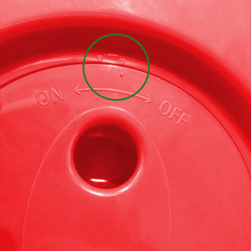 the bottom side of the pop up stool. there are two port holes which are used for turning the stool. Above these are two notches with 'on' written above one and 'off' written above the other. The stool is a vividly bright red.