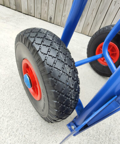 A close up view of the hard tyres on the blue hand truck. The tyres are a hard plastic and they have an internal red metal rim with a bright blue protective cap covering the centre