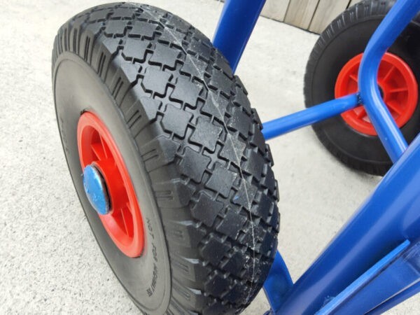 A close up view of the hard tyres on the blue hand truck. The tyres are a hard plastic and they have an internal red metal rim with a bright blue protective cap covering the centre