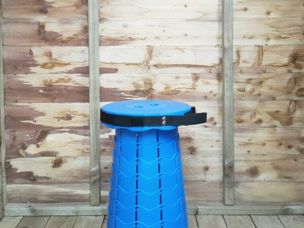 The Blue pop up stool in bright blue against the internal wooden wall of the rustic wooden shed