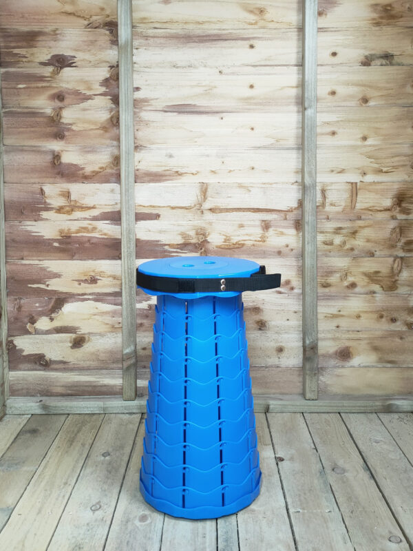 The Blue pop up stool in bright blue against the internal wooden wall of the rustic wooden shed