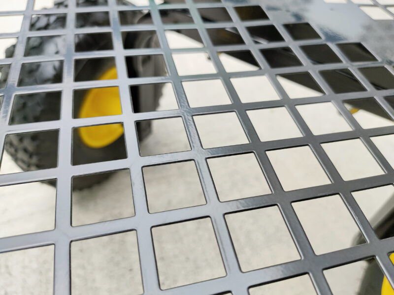 The detail of the mesh at the bottom of the mesh cart. It is a semi-matte painted black steel and the wheels are visible through the mesh.