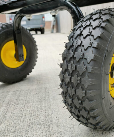 A close up view of the thick tyres on the mesh cart. They are black rubber with an internal, bright yellow rim. They have thick grooves and they are 25cm in diamter and they are 8cm thick.