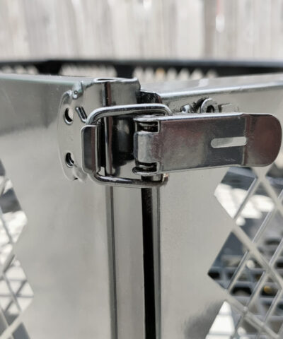 Teh locking-clasp mechanism on the mesh cart edges. It is a thick black clasp that has a metal ring around it, locking it into place