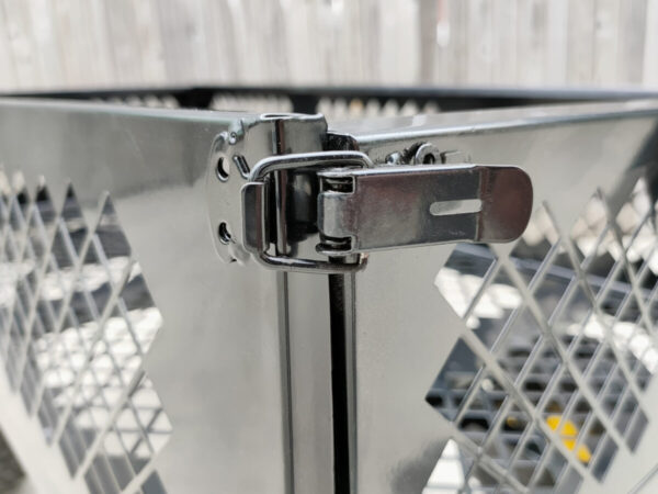 Teh locking-clasp mechanism on the mesh cart edges. It is a thick black clasp that has a metal ring around it, locking it into place