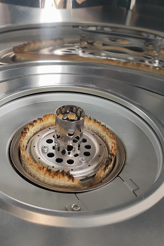 An animated gif showing the inside of a wick heater with the wick exposed. An electric lighter appears from camera right, turns on and instantly ignites the wick into a large amount of flames