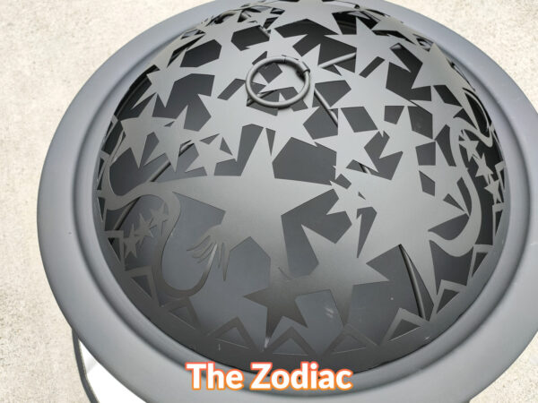 A top view of the motif on the lid of the zodiac fire pit. There are various different sized stars, a dragon's tail and some small circle on it. It's a satisfyingly nice matte black
