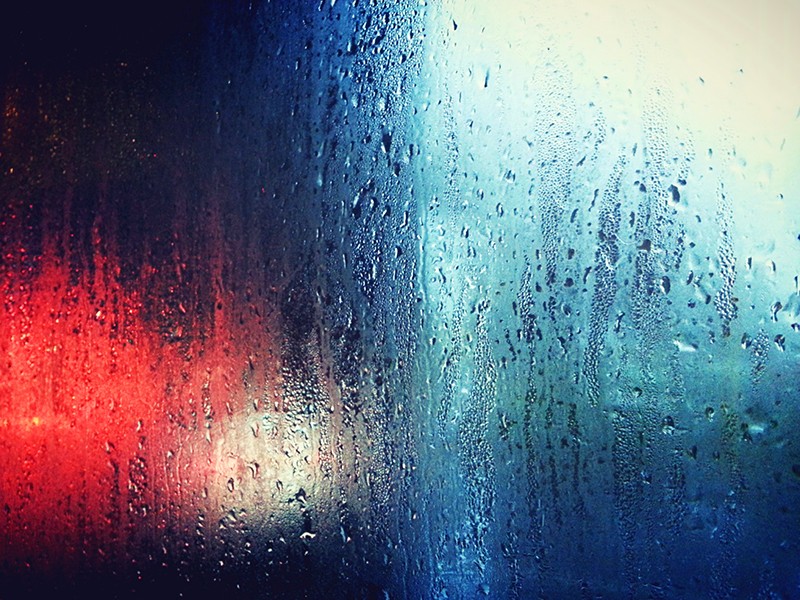A cold blue and red background with a window with heavy condensation in the way