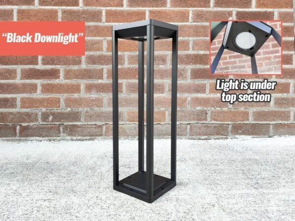 The 'Black Downlight' LED Solar Garden Light against a brick wall