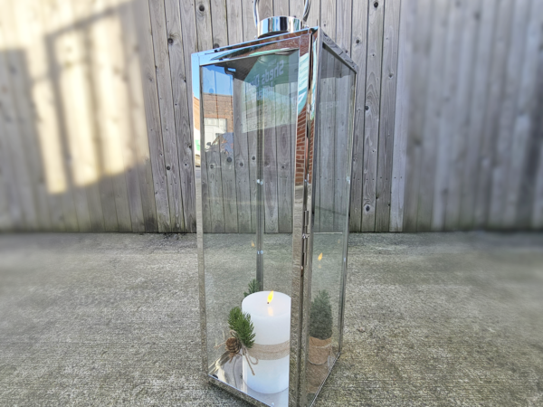 A stainless steel candle holder lantern with a small white candle inside