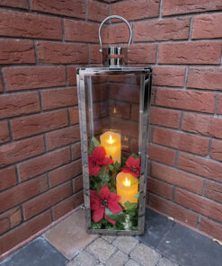 A stainless steel lantern candle holder against a redbrick wall