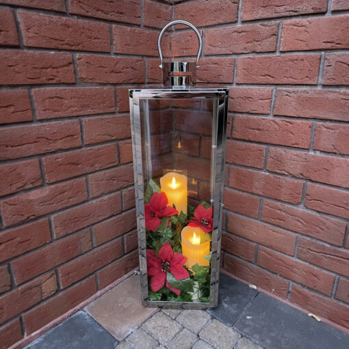 A stainless steel lantern candle holder against a redbrick wall