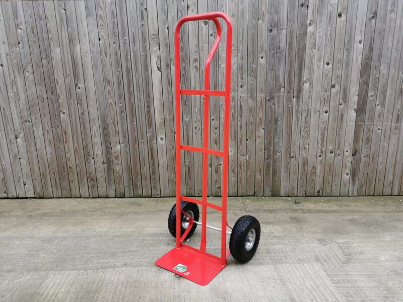 The image shows the red P handle trolley with a wooden fence behind it. 
