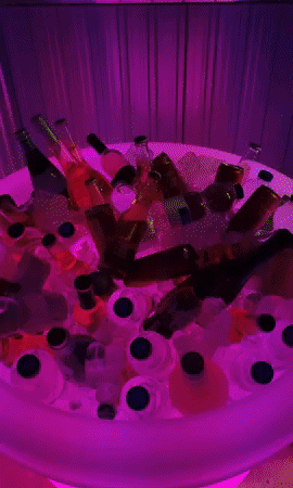 a moving gif showing an Almore pot filled with ice, beers, wines and cans. A hand comes in from the right, picks up a beers and disappears to the right. The plant pot is changing colours the whole time this is happening.