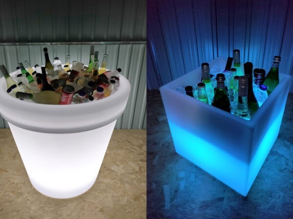 The large Almore plant pot filled with cans of coca cola, water bottles and mountains of ice on one side. To the other side the cube plant pot is glowing blue, it's also filled with drinks and ice.