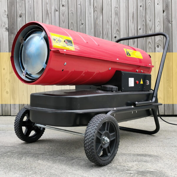 The Red, long, tubular industrial heater on a wheel base against a wooden wall. The base and wheels are black, the tube is bright red and the inside of the tube is concealed by a blue-ish metal circular grille.