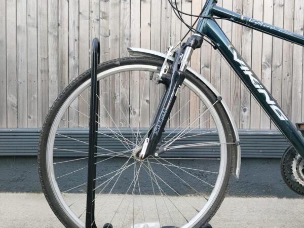 A close up, side view of the bike stand with a bicycle parked into it.