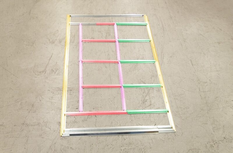 The base frame of a steel shed with each panel in a different colour, highlighting how many pieces make up the base