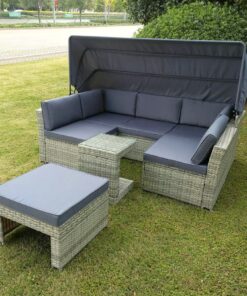 The outdoor rattan garden sofa set from sheds direct Ireland outside on a green lawn. The unit it a rattan, light-brown colour and the cushions and awning are a dark grey colour.