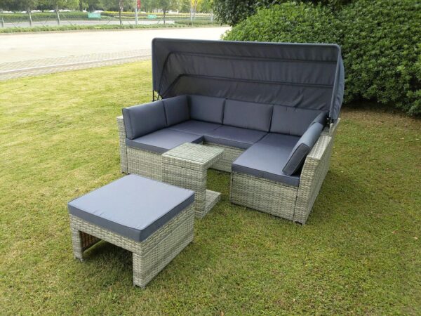The outdoor rattan garden sofa set from sheds direct Ireland outside on a green lawn. The unit it a rattan, light-brown colour and the cushions and awning are a dark grey colour.