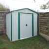 8ft x 6ft Steel Garden Shed in off-white in the corner of a garden