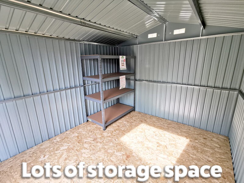 an internal view of the 9ft x 10ft steel shed showing the grey panelled walls, a brown plywood floor, a large shelving unit and light coming through the built-in vents. It reads 'lots of storage space' on top.