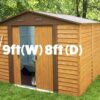 9ft x 8ft Metal Garden shed sitting in a lovely garden with a shovel leaning against it.