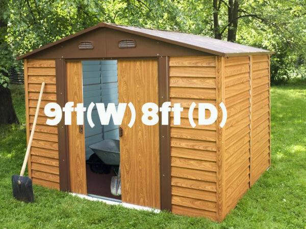 9ft x 8ft Metal Garden shed sitting in a lovely garden with a shovel leaning against it.