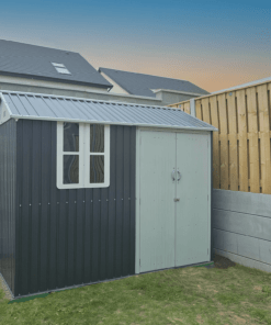 The steel cottage shed in the corner of a new garden at sunset