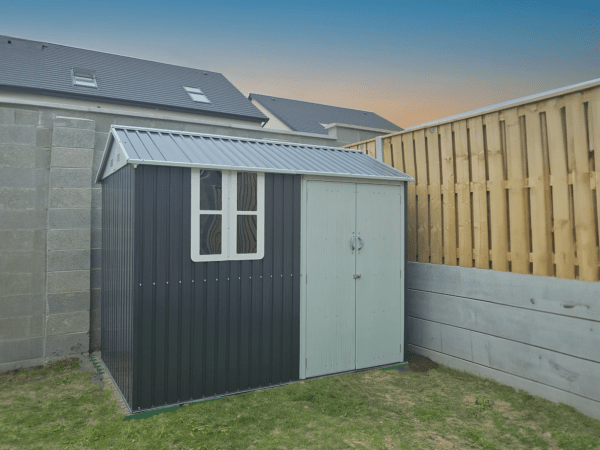 The steel cottage shed in the corner of a new garden at sunset