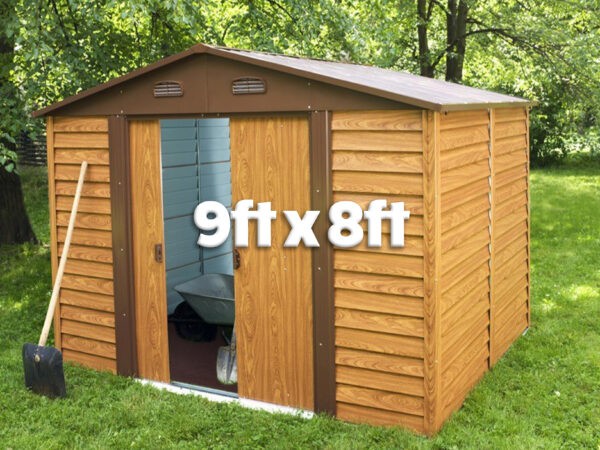 The woodgrain shed seen from a 45 degree angle. The door is open and inside the shed has grey walls and there is a dulled metal wheelbarrow and spade visible. Outside the shed is a bright orange-brown colour and there is grass and trees surrounding it. On top the text reads '9ft x 8ft'