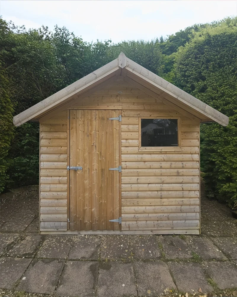 Overhang wooden shed exterior, in front of a bush