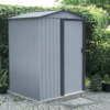 The Tiny Shed in a paved garden, in front of a large bush