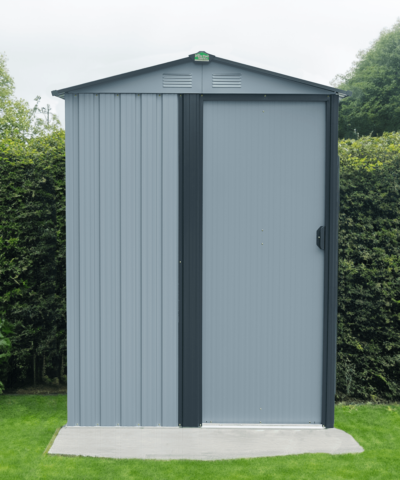 The TIny shed in a garden against a mid-sized, dark green bush