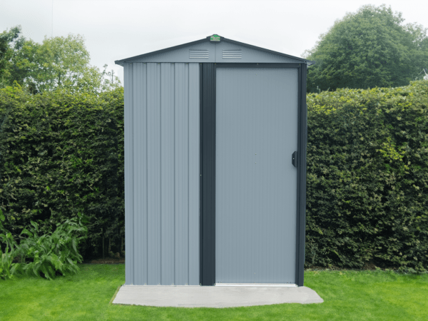 The TIny shed in a garden against a mid-sized, dark green bush