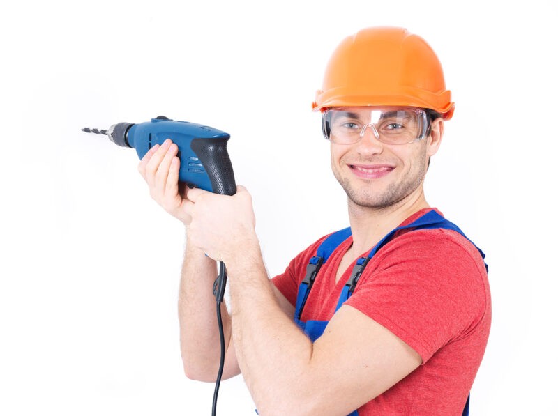 Portrait of a smiling man drilling a hole in the wall.