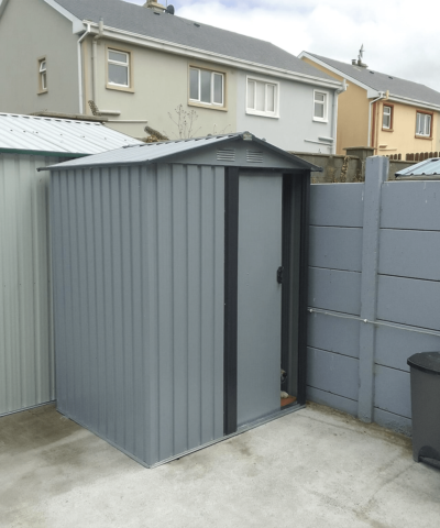 The Tiny Shed in the corner of a garden with a dogs nose poking out the door