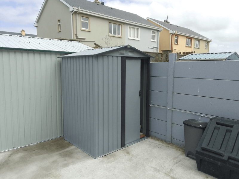 The Tiny Shed in the corner of a garden with a dogs nose poking out the door