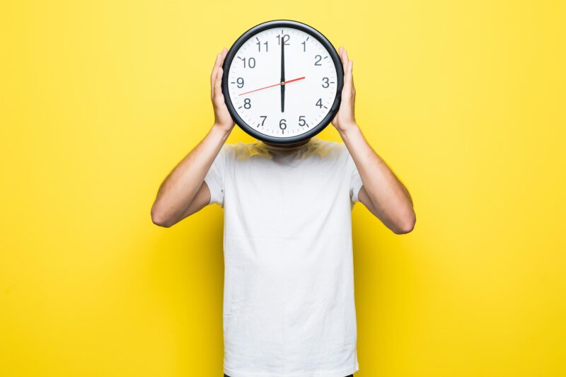 man in white t-shirt and transperent glasses hold big clock in one hand