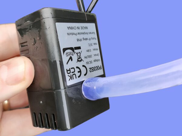 The pump from the water picture being held in a hand. There is a tube connected to the bottom of the pump