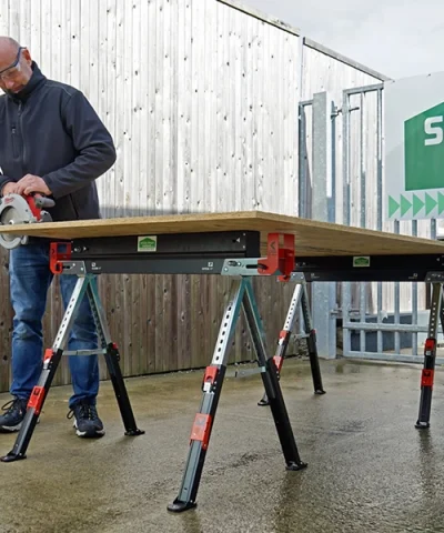 A man using a power saw on the saw horse